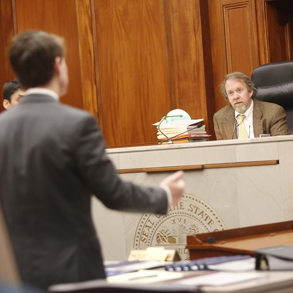 a young man stands before a judge