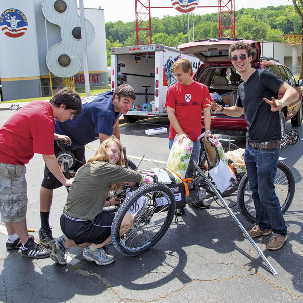 Students tinker with a tricycle in front of a silo that says U.S. space camp