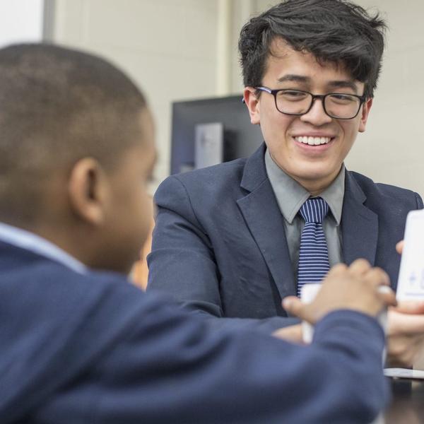A young man shows a boy a flash card.