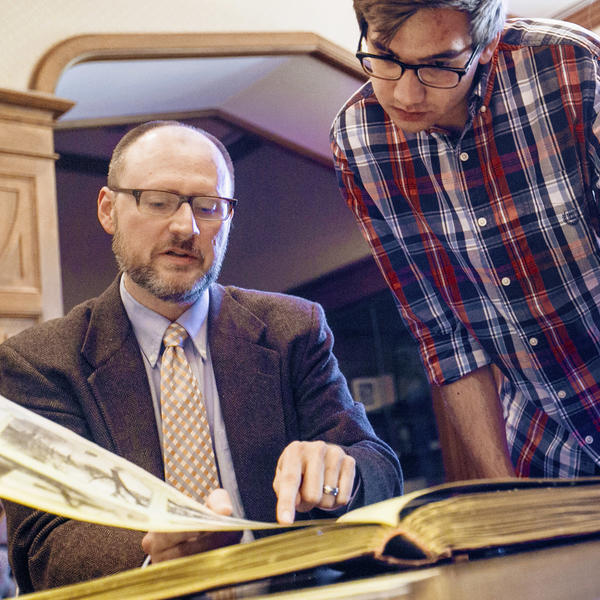 A professor and two students look at a manuscript