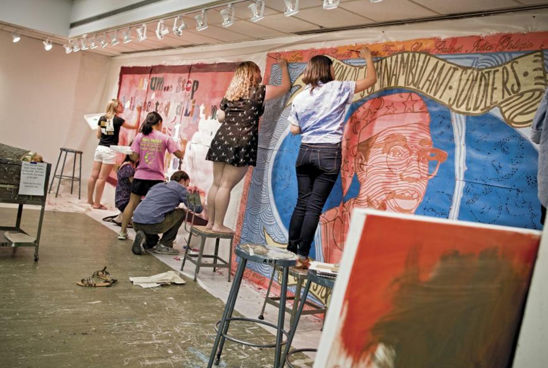 Students paint a mural on an interior wall