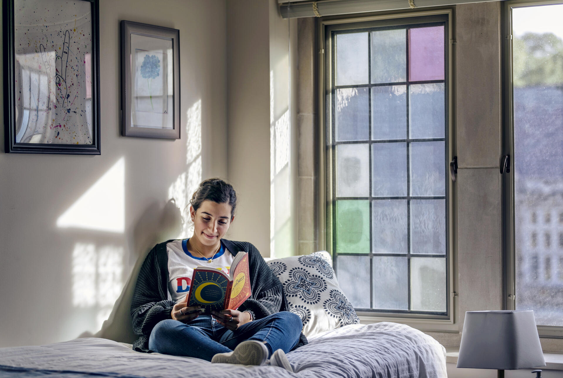 a female reading a book in her dorm room