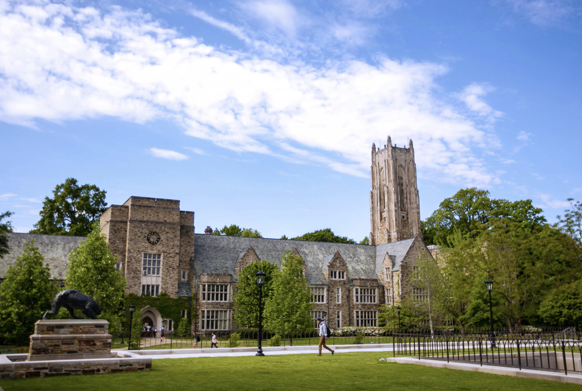 a wide shot of a Gothic stone building and a student walking 