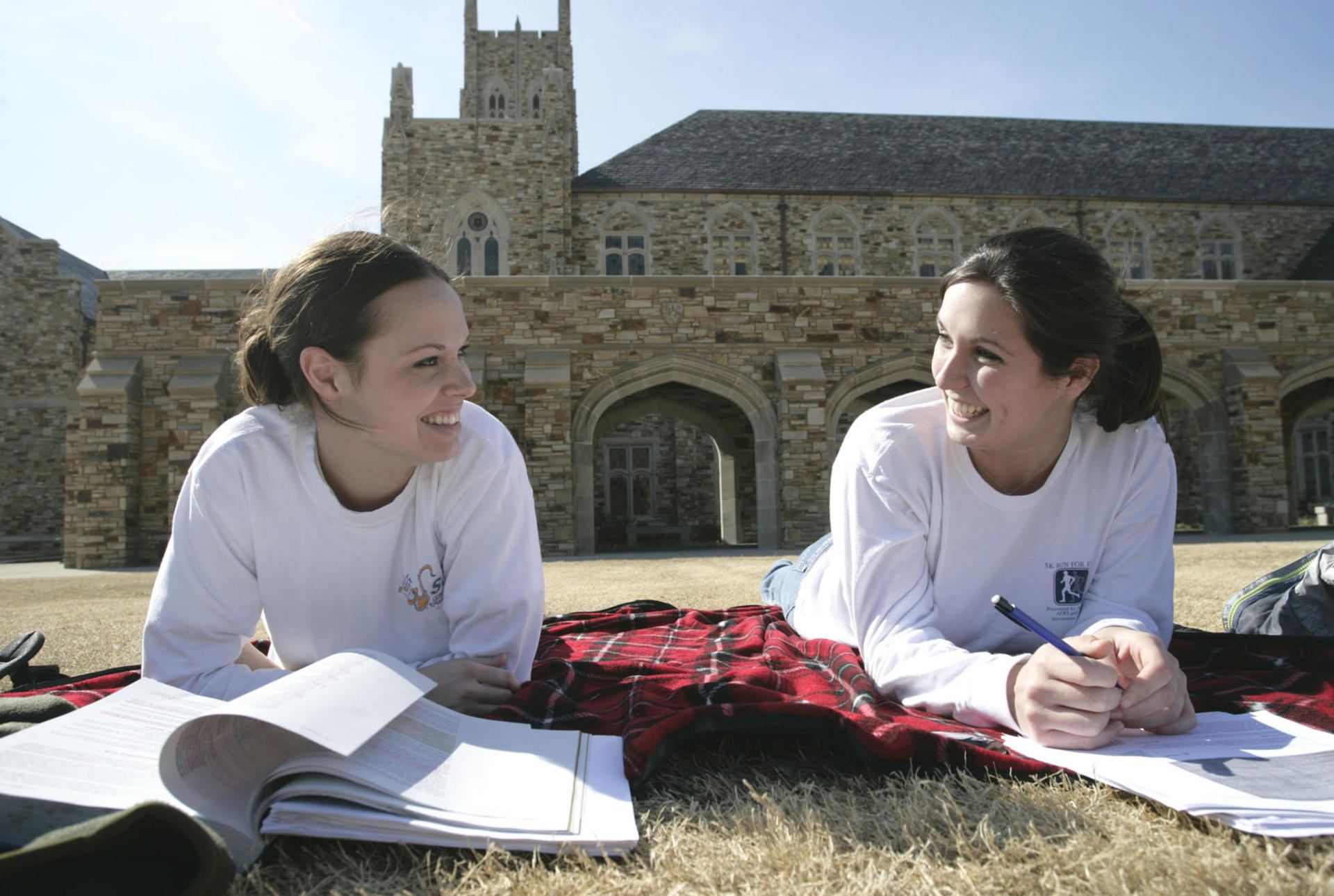 two female students study on the lawn of the library