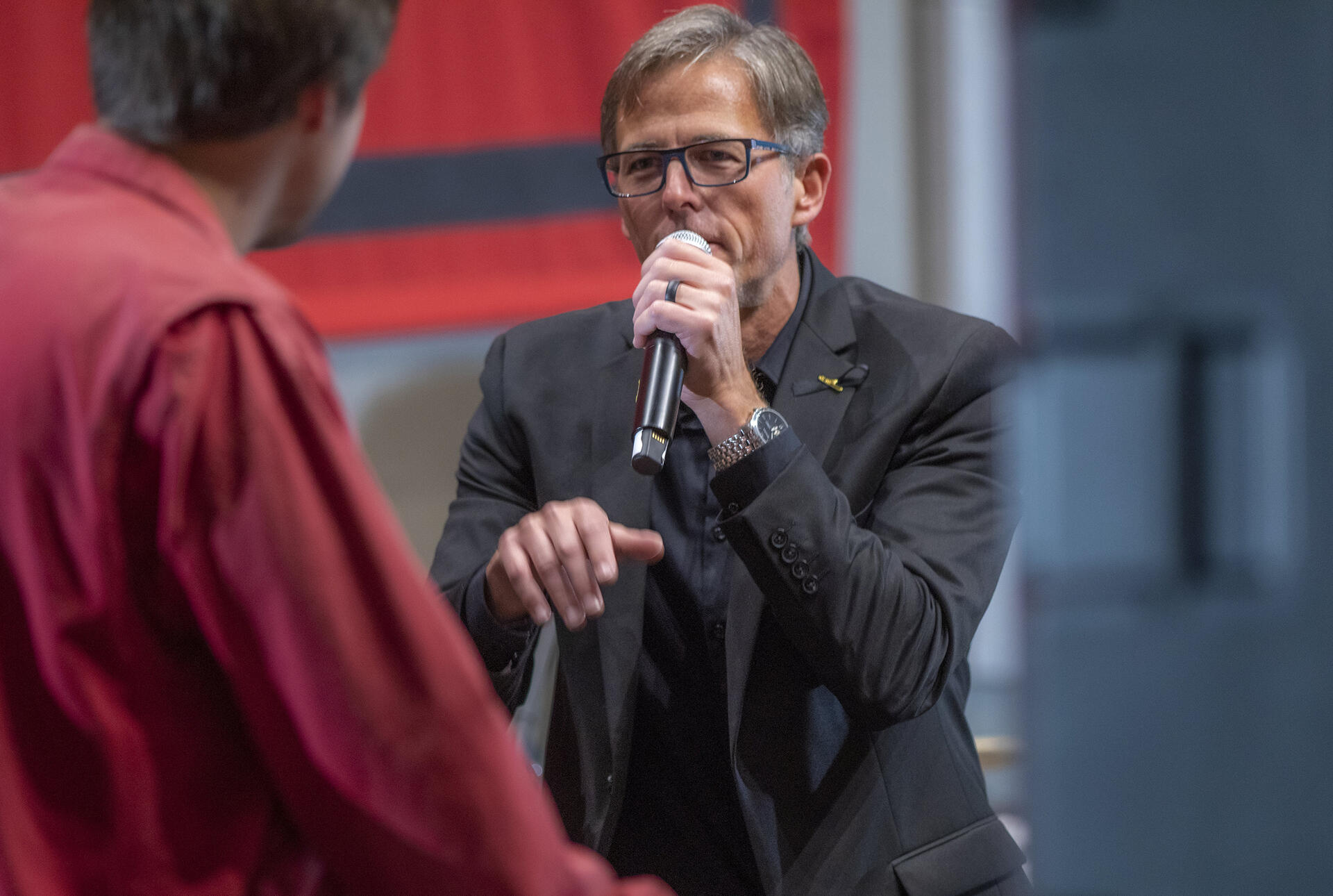 a man with glasses talks into a microphone