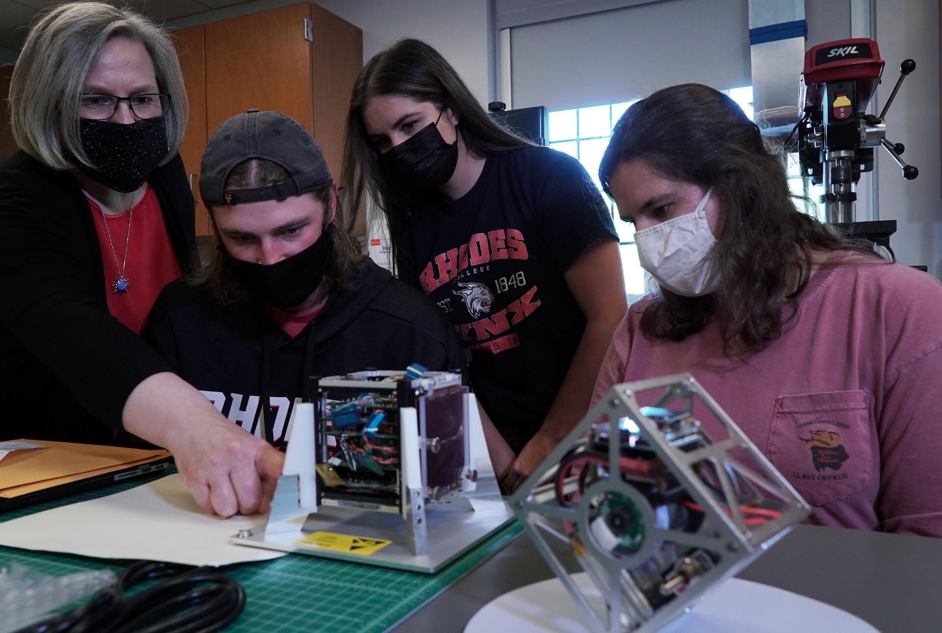a professor and students work on a satellite research project