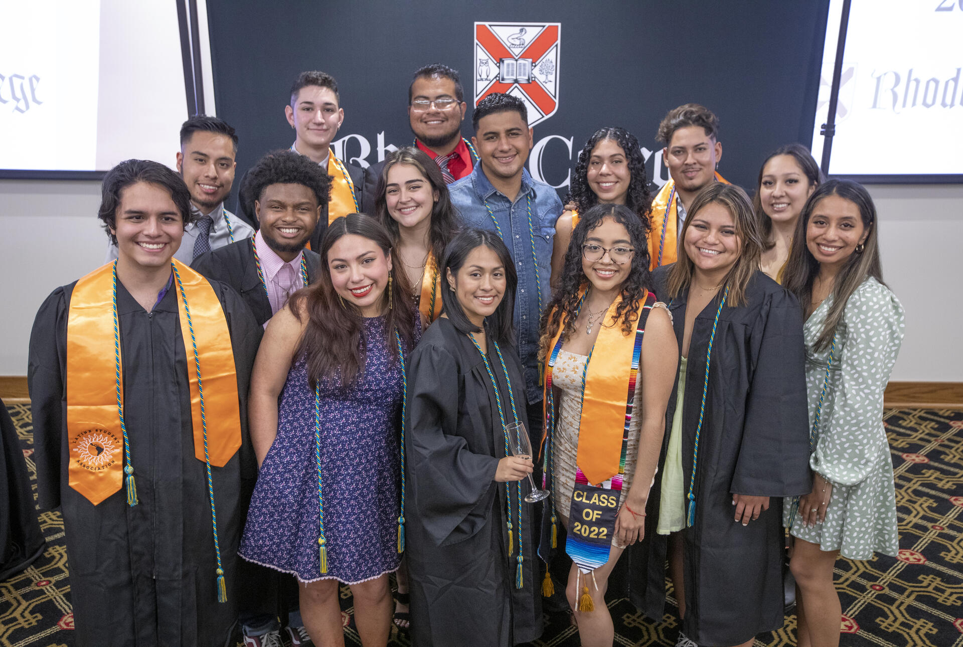 Group of Latinx students at Rhodes College wearing graduation regalia, cords, and stoles.