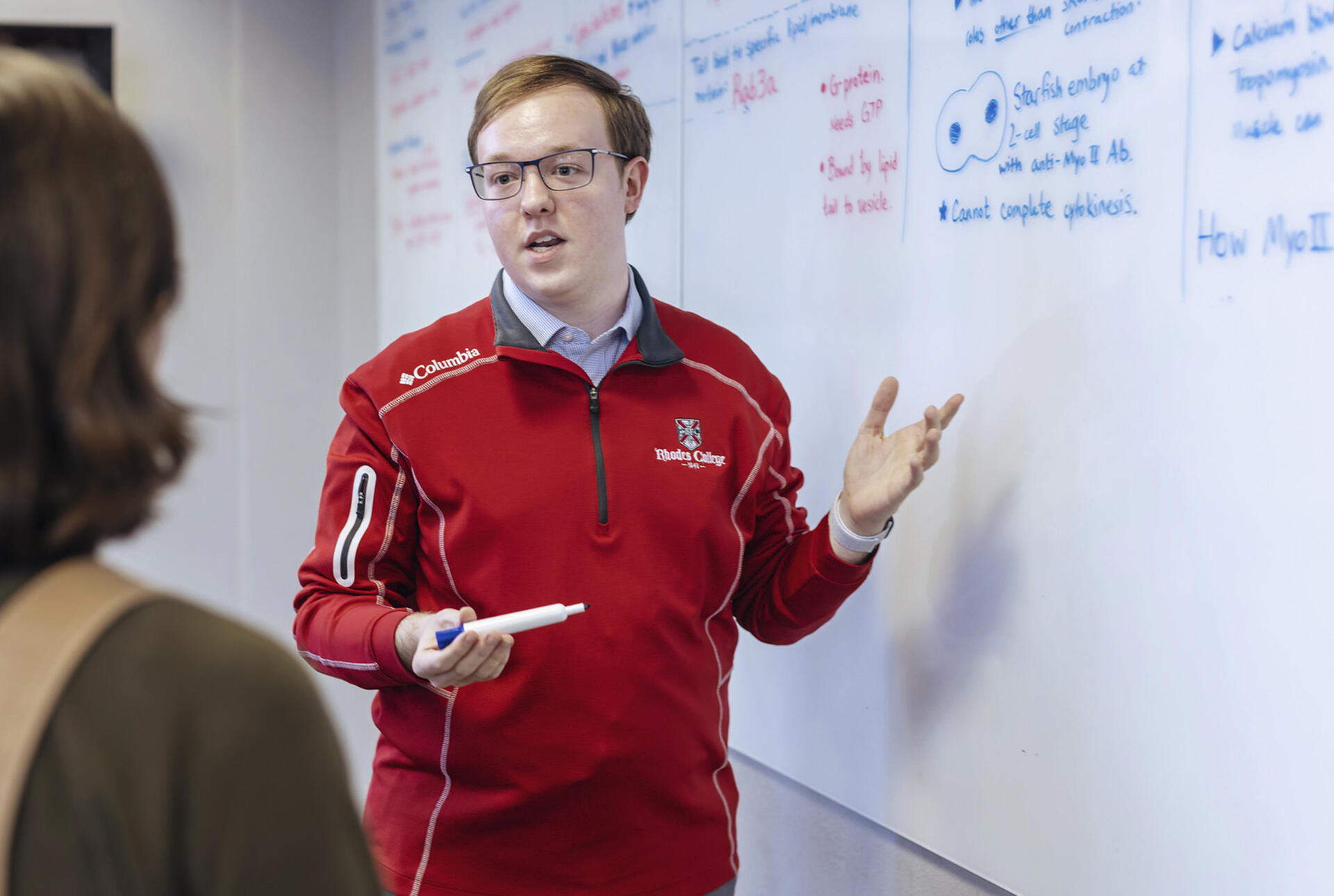 a young man gestures at a whiteboard