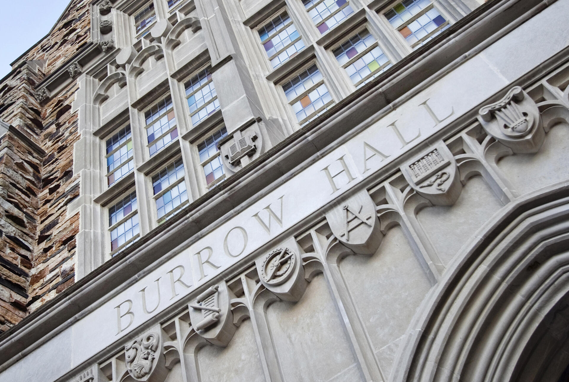 A close up of the chiseled stone that reads Burrow Hall above an arch and below a row of windows
