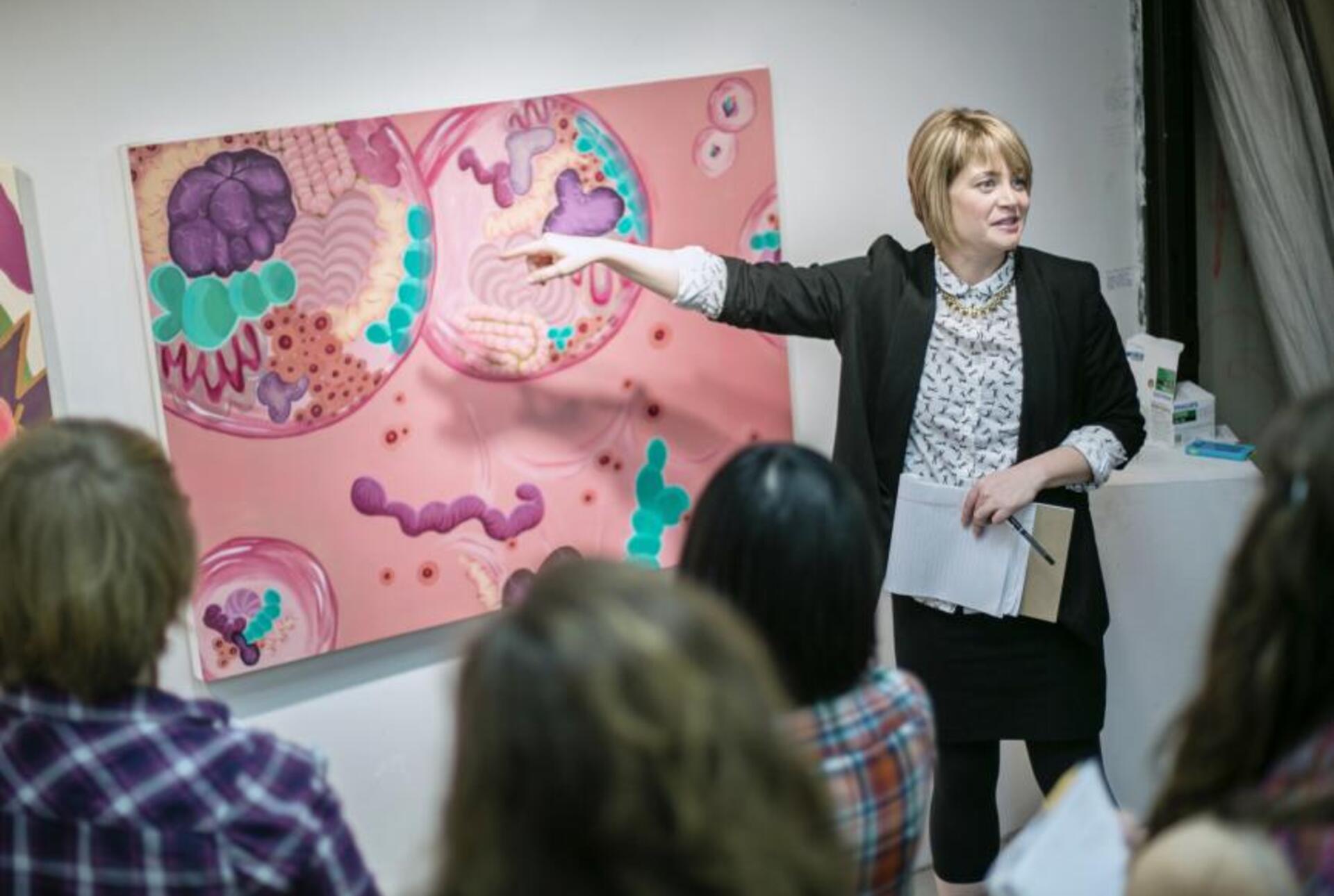 A professor points to a pink painting