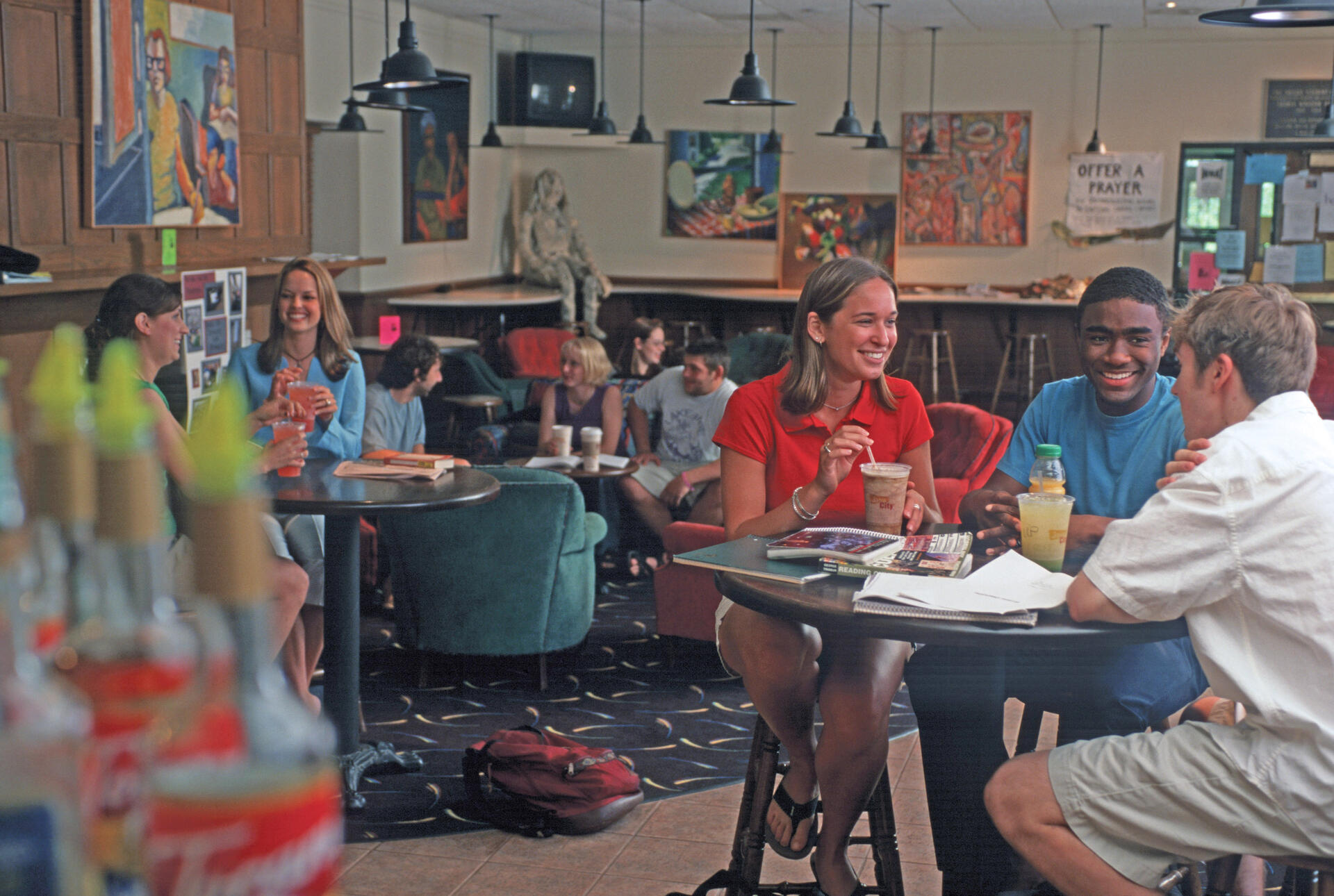 people sit at round tables with beverages in a cafe with lots of art