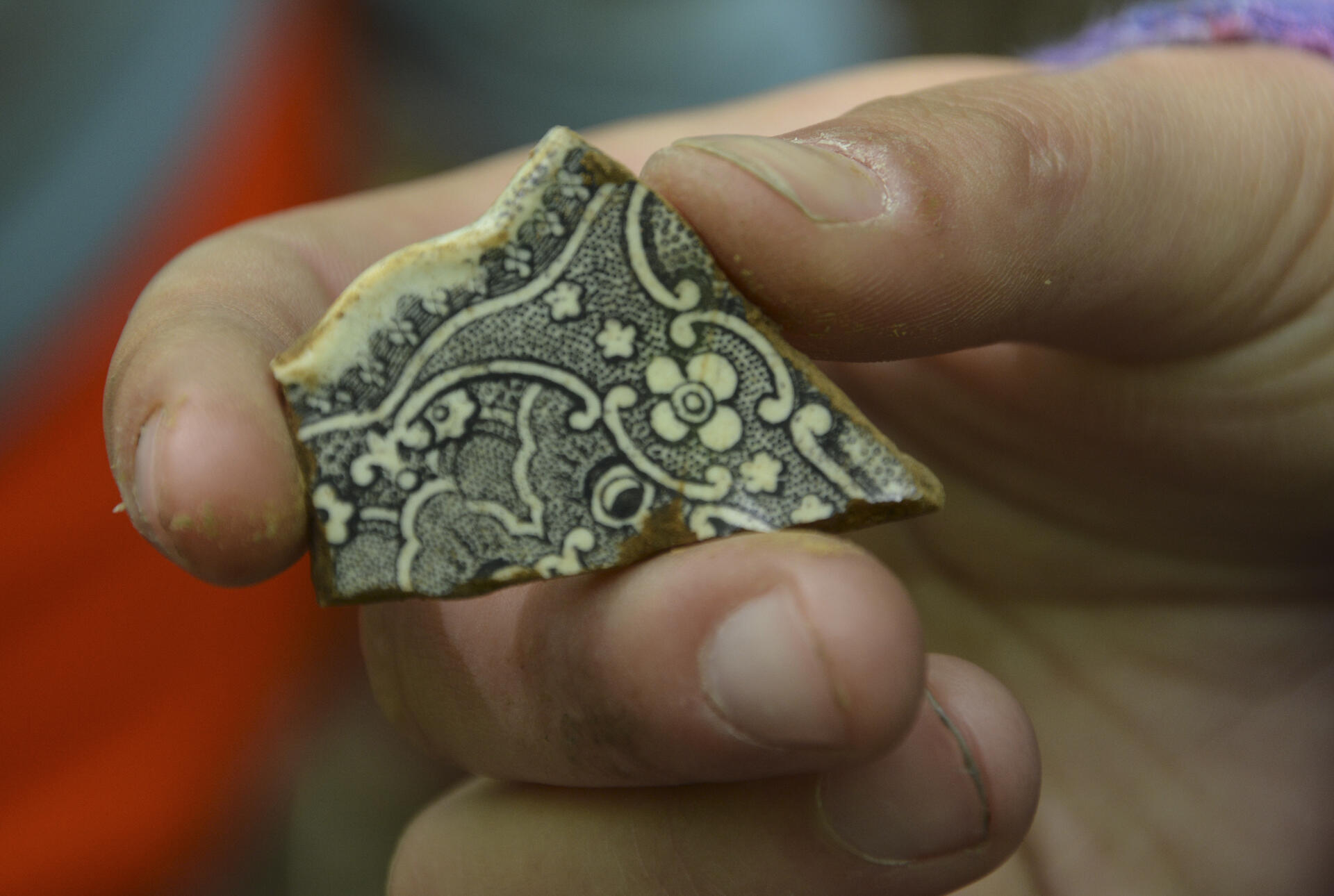 A fragment of a clay pot, intricately decorated with black line drawings.