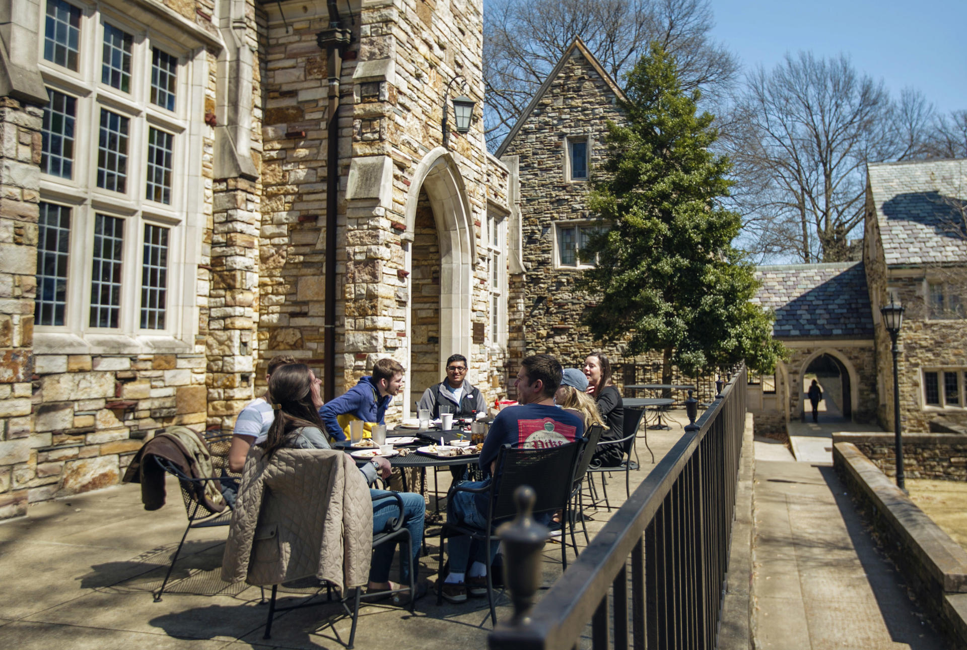 students on a patio of a gothic stone building