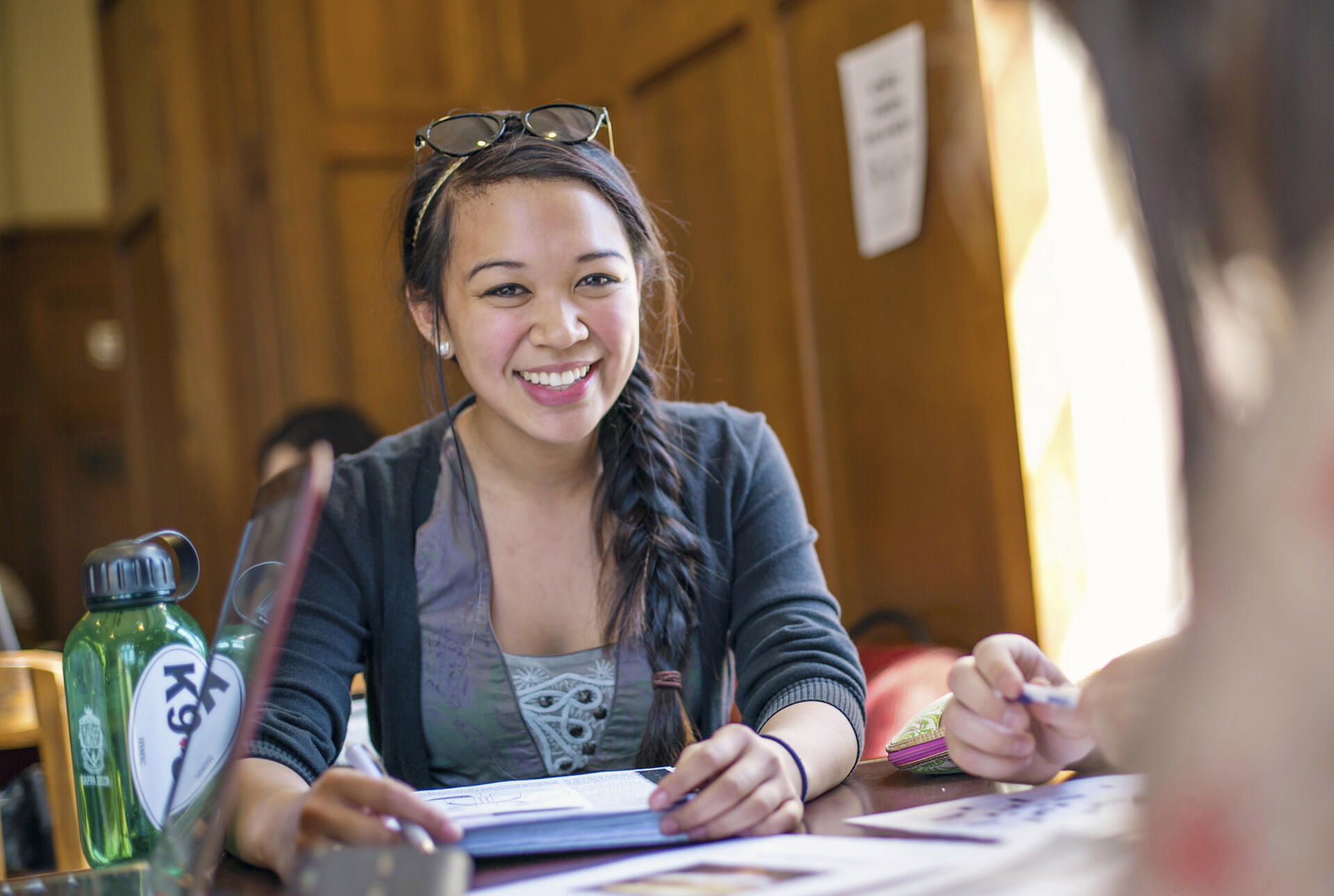 a student smiling and studying in the refectory
