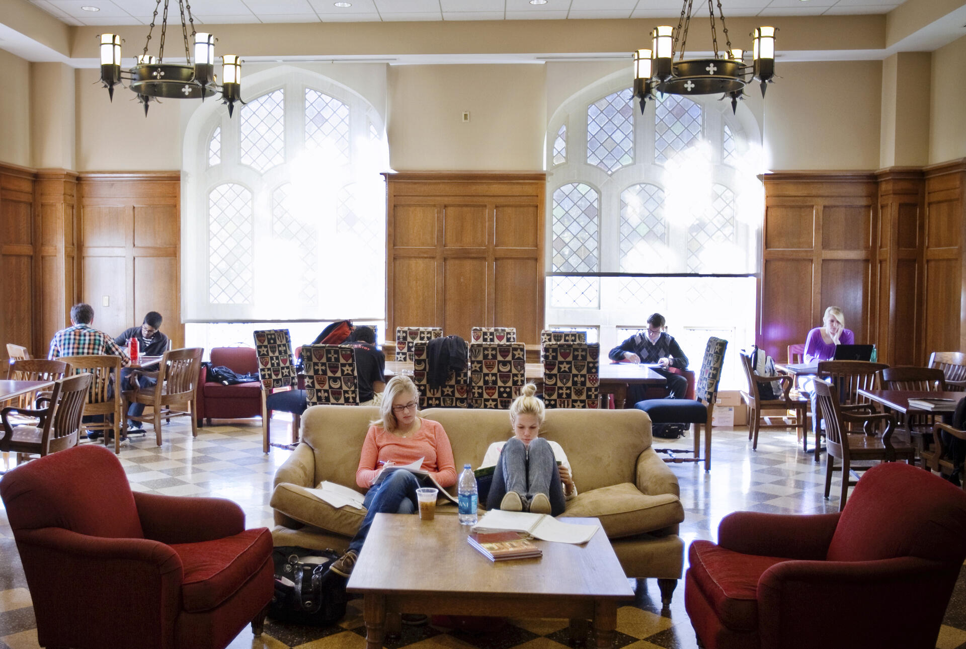 Two foregrounded students sit on a couch in the Middle Ground coffee shop