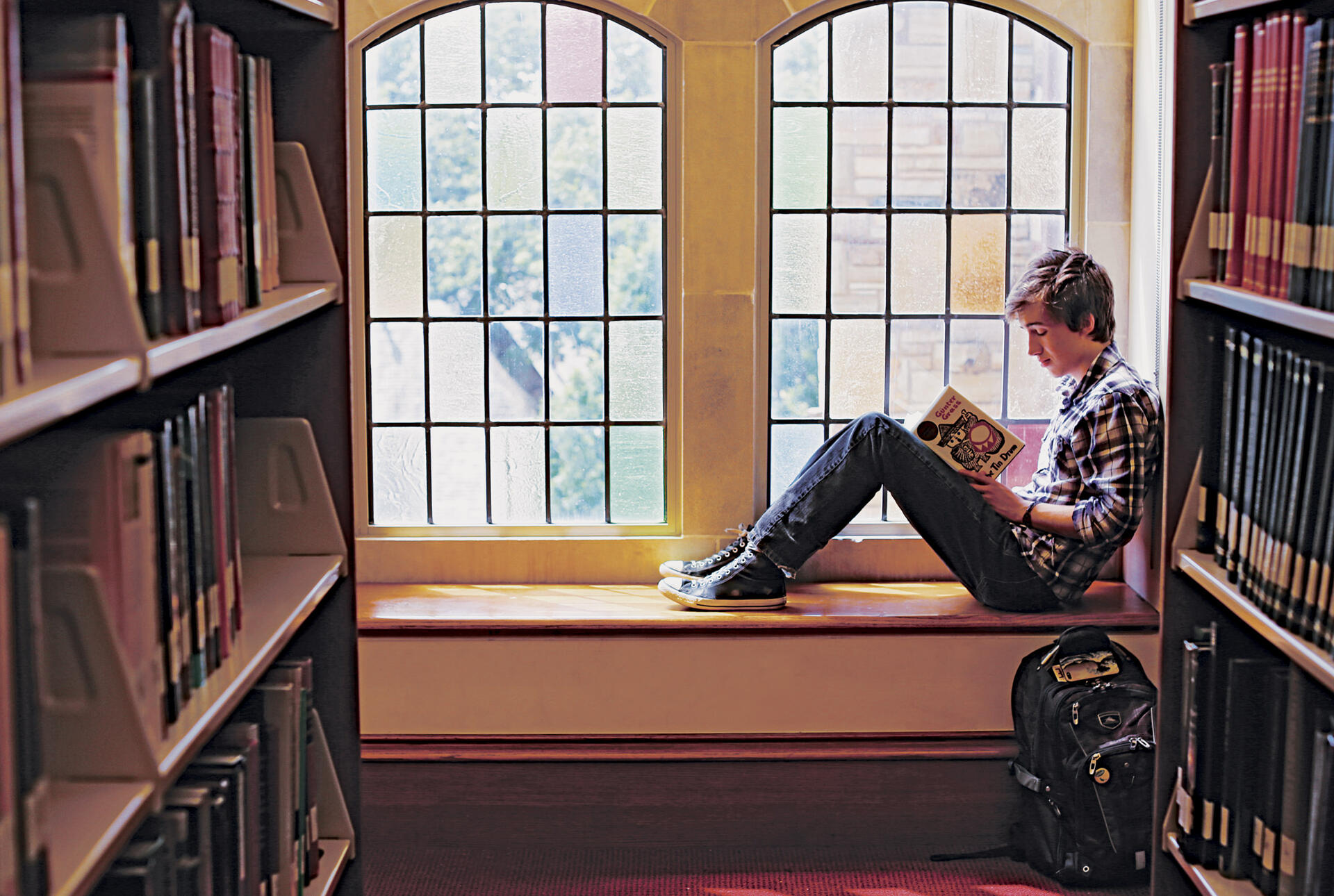 student reading a book in front of a window