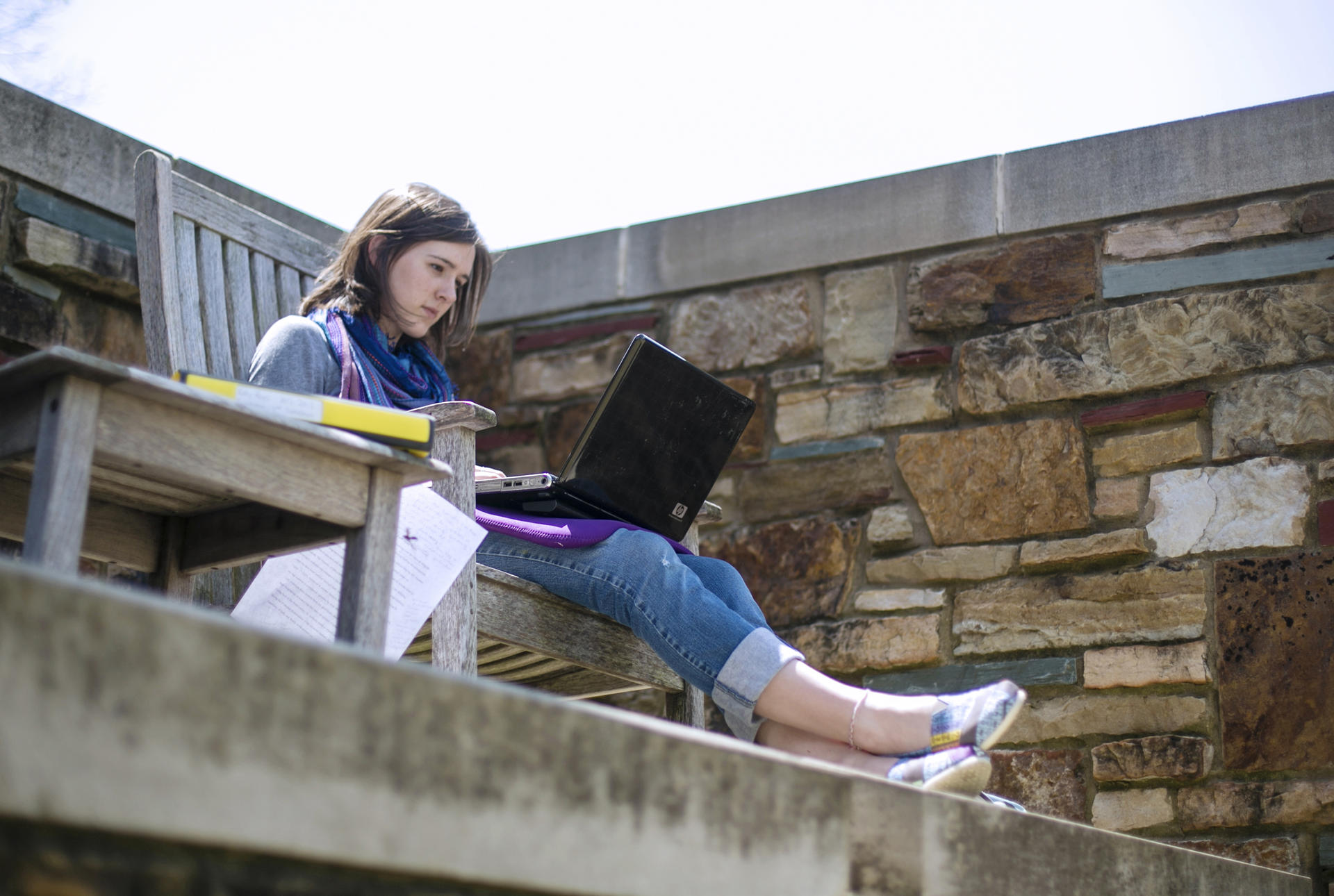 A student sitting on a bench with a laptop