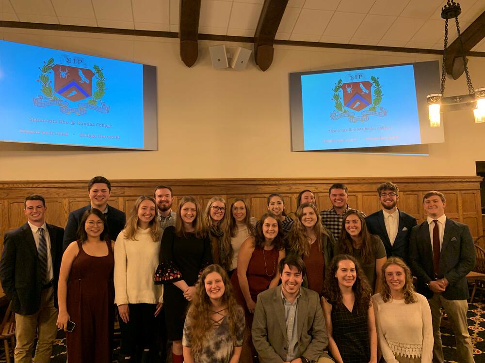 A group of student inductees standing together in a word-panelled room