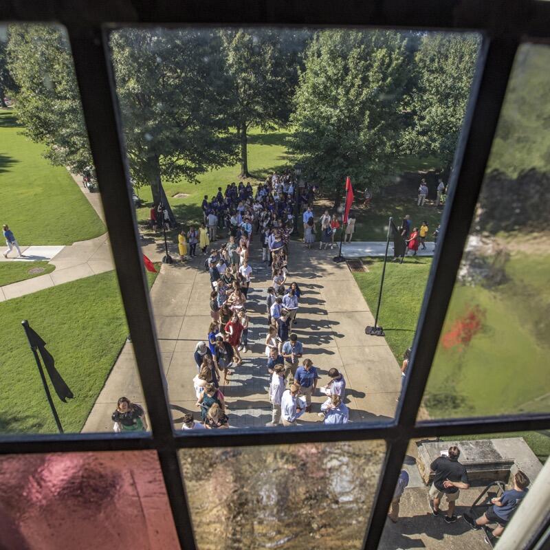 Students lined up in the quad as seen through a stained glass window.