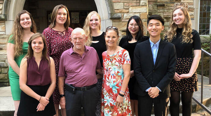 a group of students stand on steps with an older couple