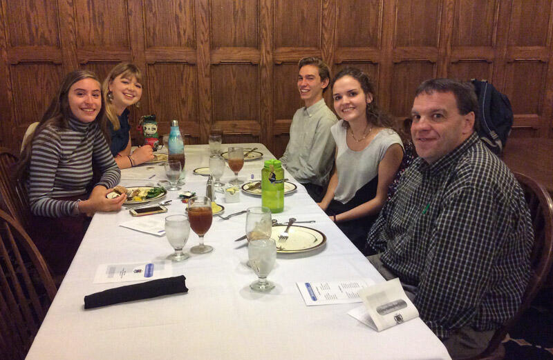 a professor with students sit at a table