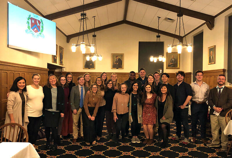 professors and students standing together in a wood-panelled room