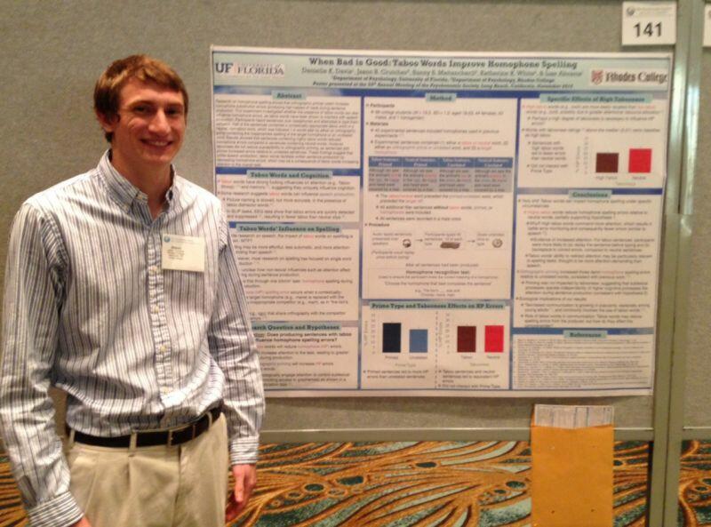 a male student stands in front of a poster board