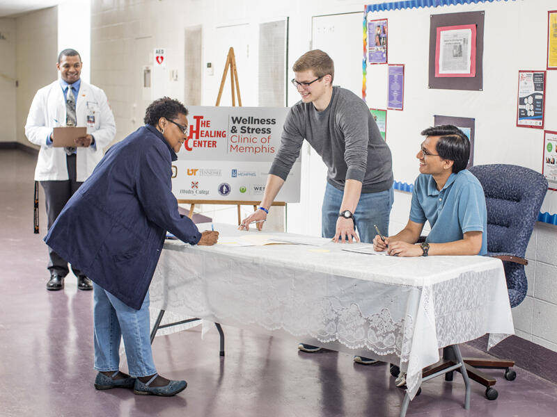 two students greet a patient at a wellness clinic