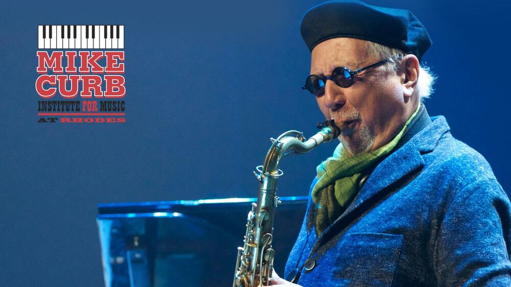 A man in sunglasses and a flatcap plays the tenor sax.