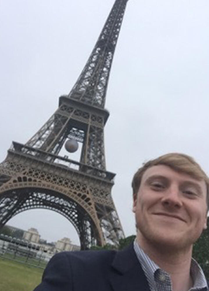 a male student in front of the eiffel tower