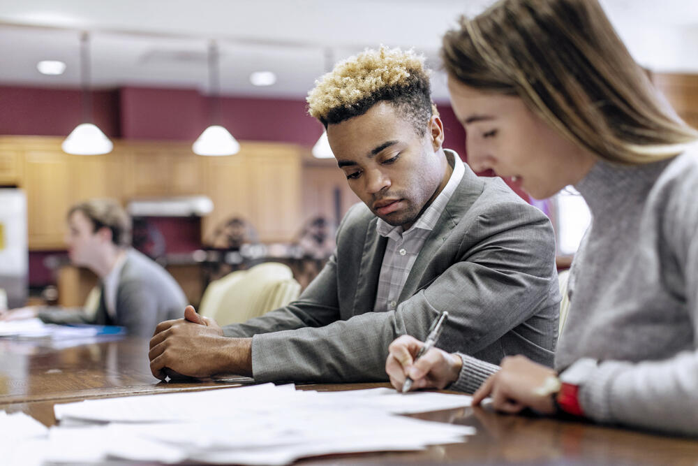 a male and female student look over some papers