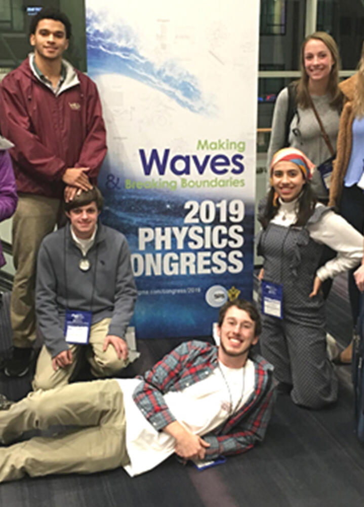 students stand in front of a sign for a physics congress
