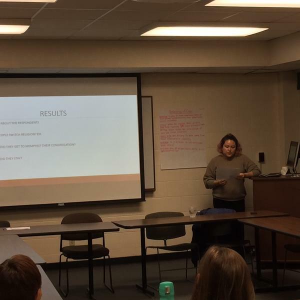 a young woman speaks in front of a class