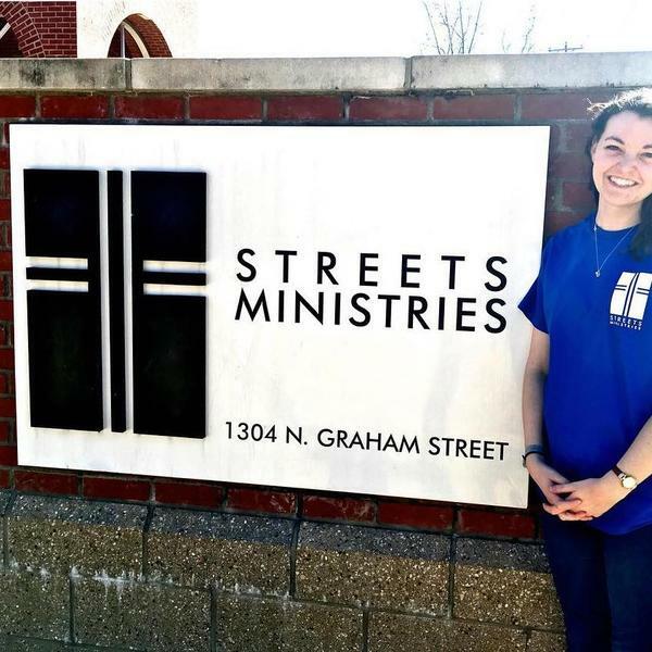 a young woman stands by a sign for Street Ministries