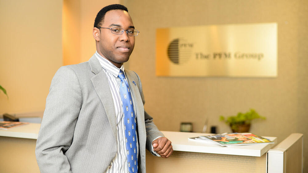 a young African American man in an office looks at the camera