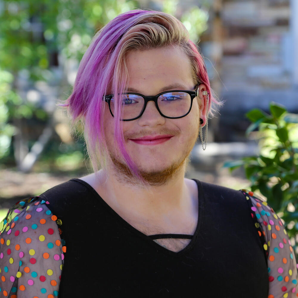 a young person with pink hair and glasses