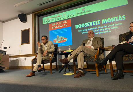 three men sit on a stage during a panel discussion