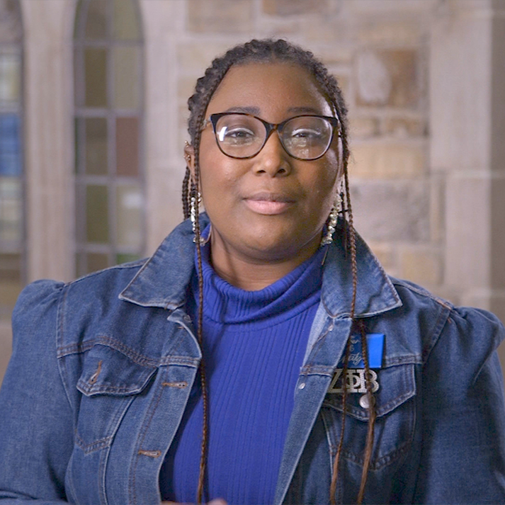 A young black woman in a blue mock turtleneck and stylish denim jacket.