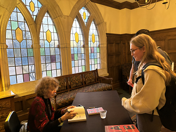 a woman signs a book for a female student