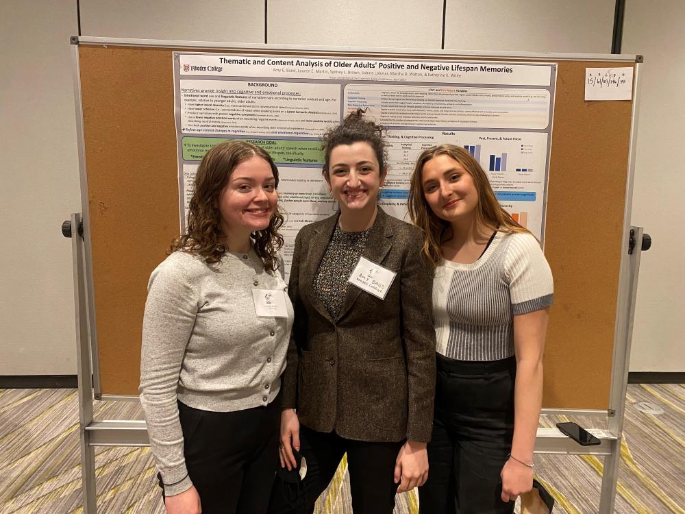 three young women stand next to a poster