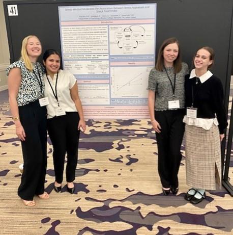 four students pose in front of a research poster