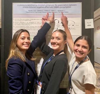 a group of students point to a research poster