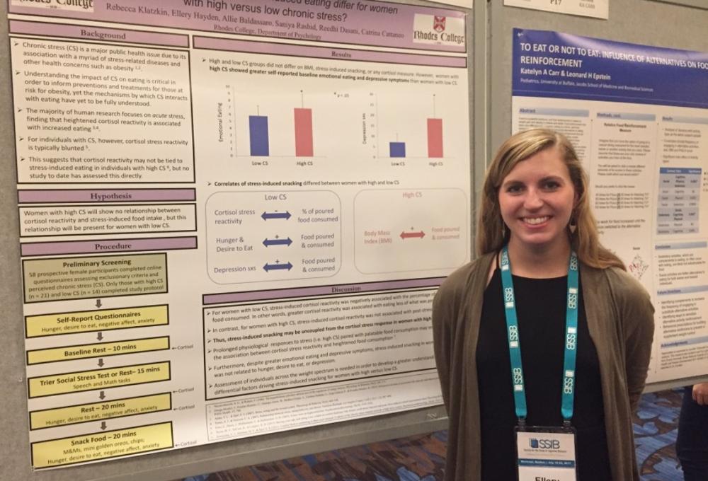 a student poses in front of a research poster
