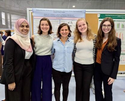 a group of students pose in front of a research poster