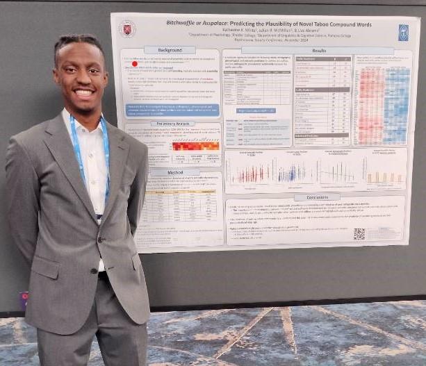 a young man stands next to a poster