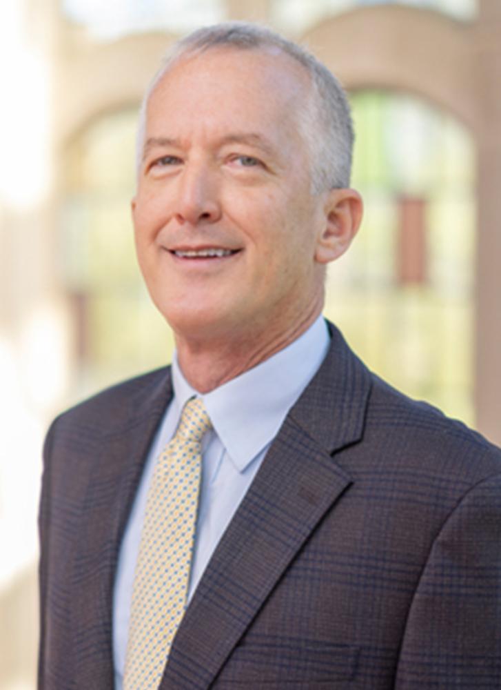 a man in a suit and tie smiles at the camera