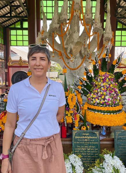 a woman with short hair in front of a statue of a Buddhist god