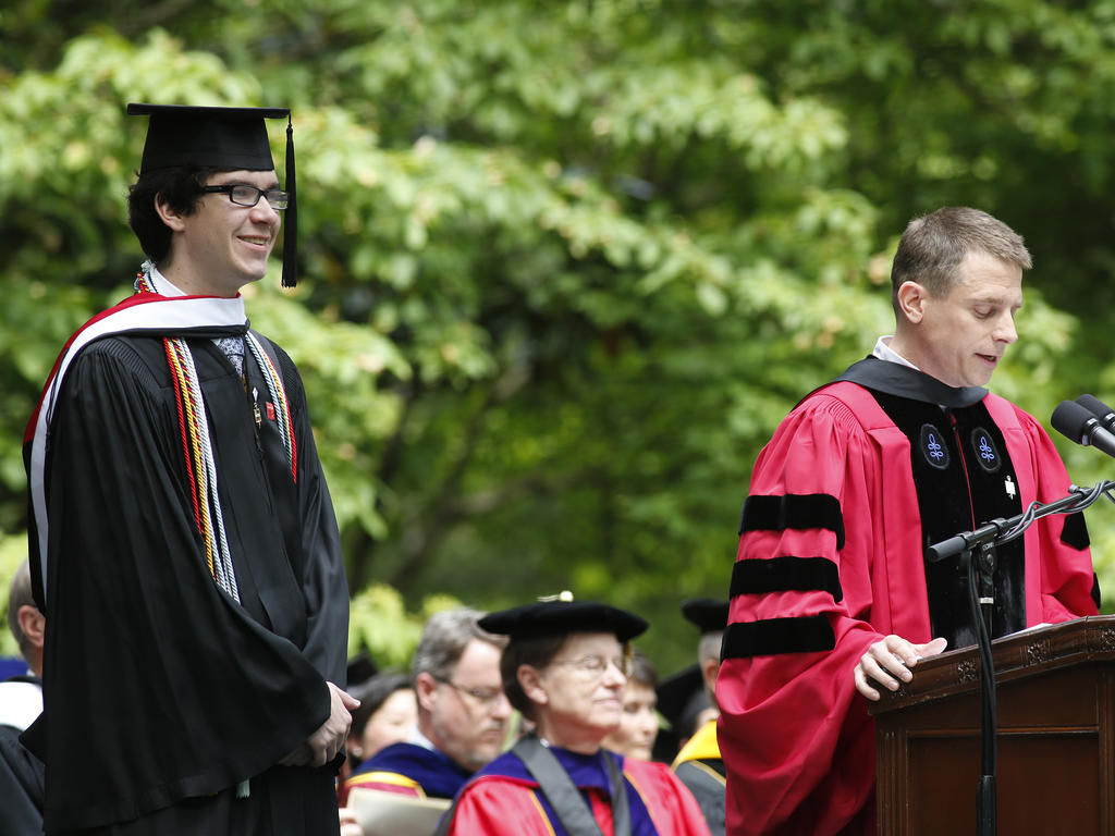 a male student receives an award from a professor