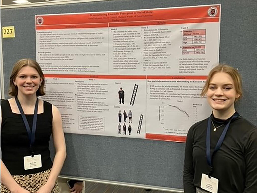 image of two Rhodes College students standing in front of a research poster