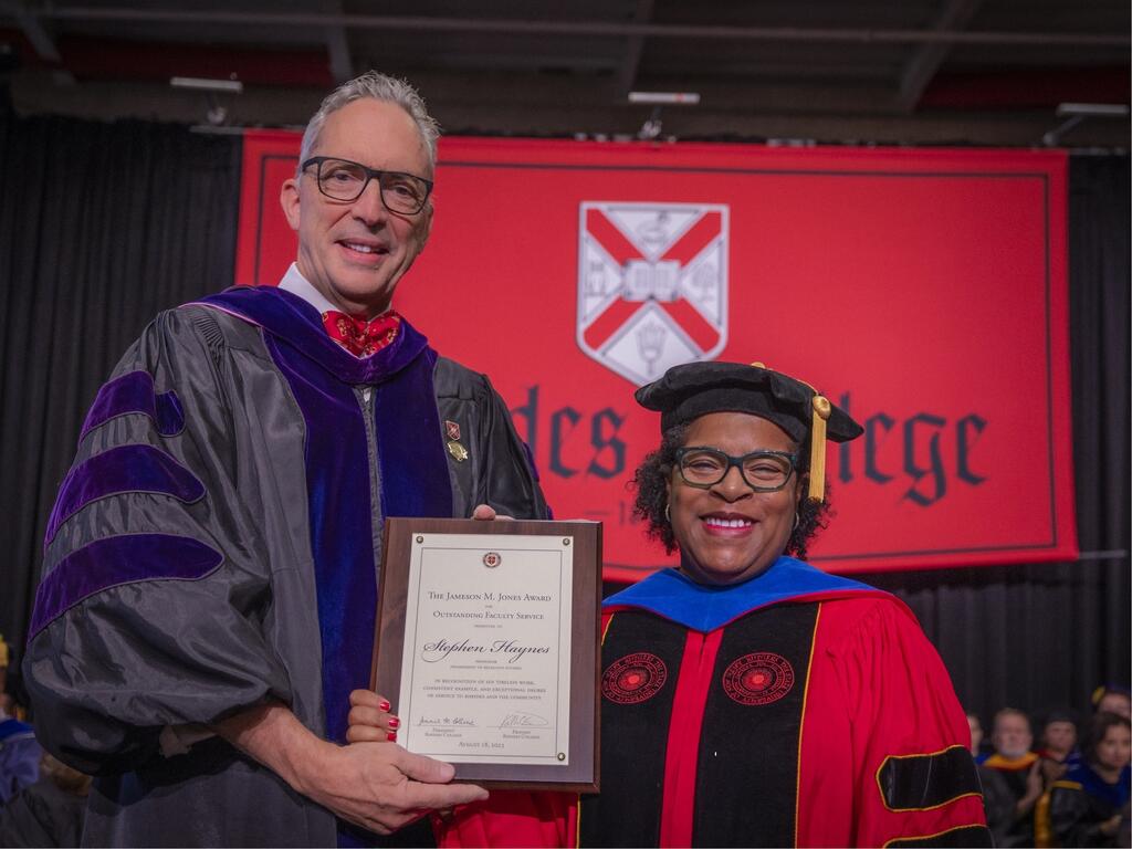 image of Rhodes College professor holding a plaque and standing next to the provost